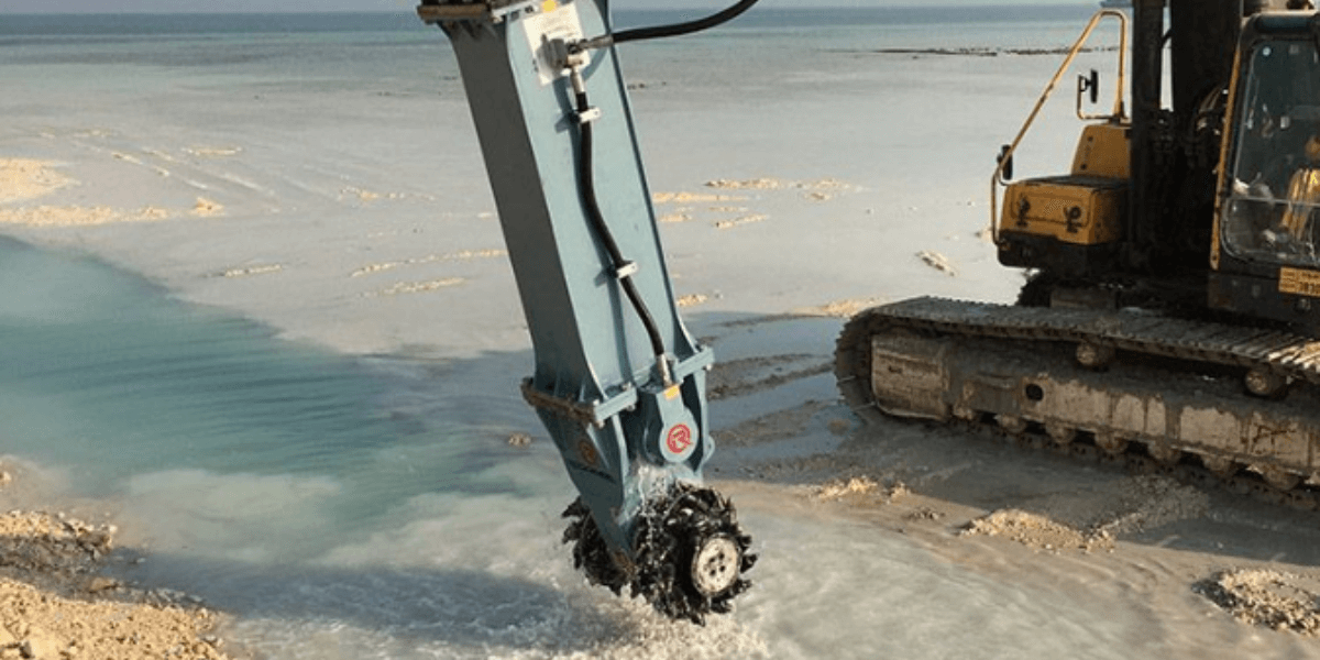 An excavator equipped with a rockwheel drum cutter operating in a shallow water environment